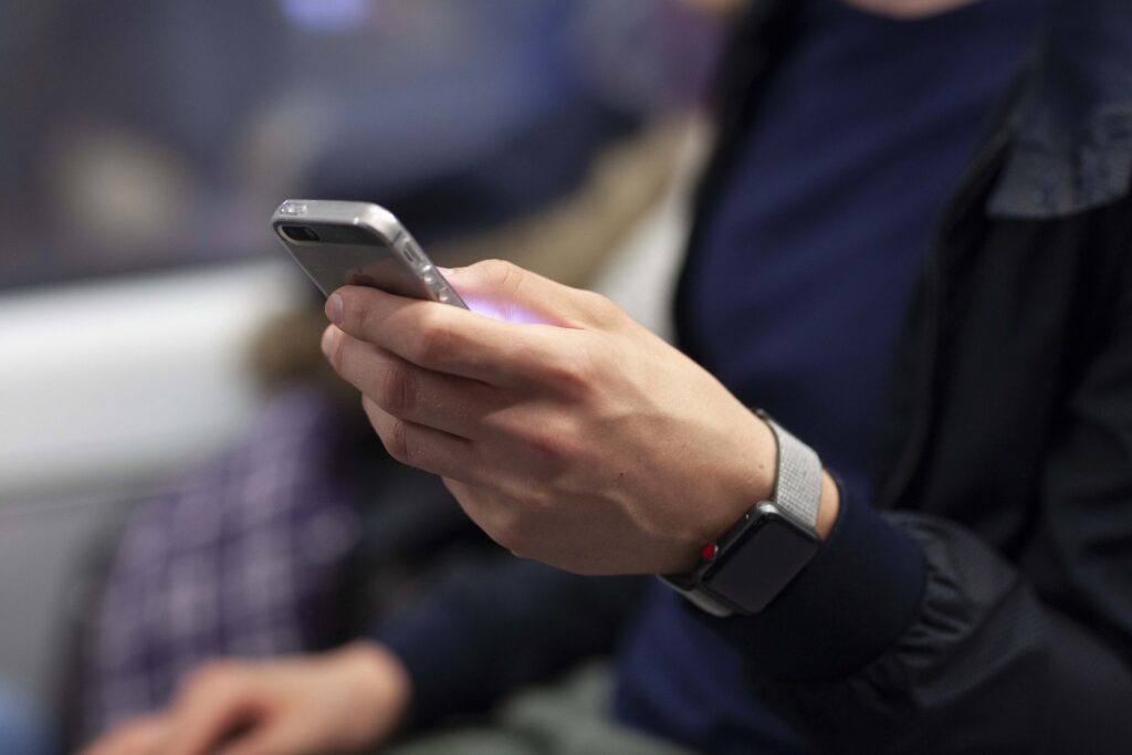 Mann mit Smartwatch am Handgelenk und Smartphone in der Hand Detailansicht