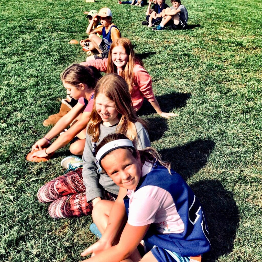 Kinder sitzen nebeneinander auf einer Wiese
