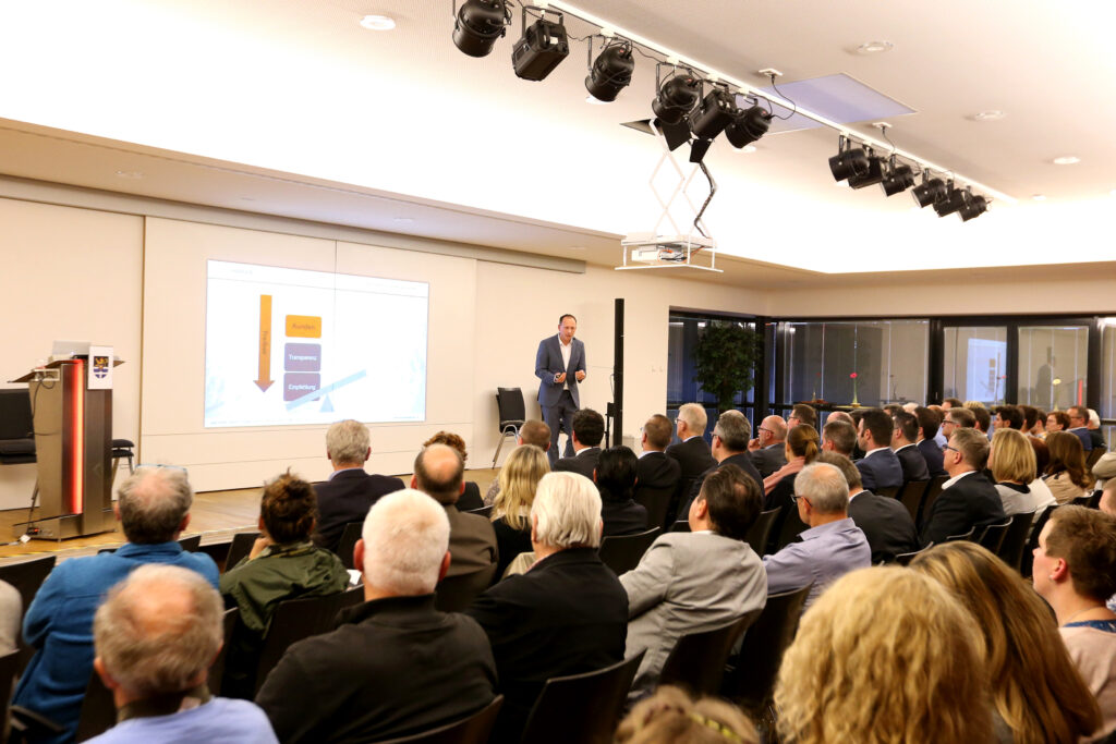 Referent bei einem Vortrag vor mehreren Zuschauerinnen und Zuschauern