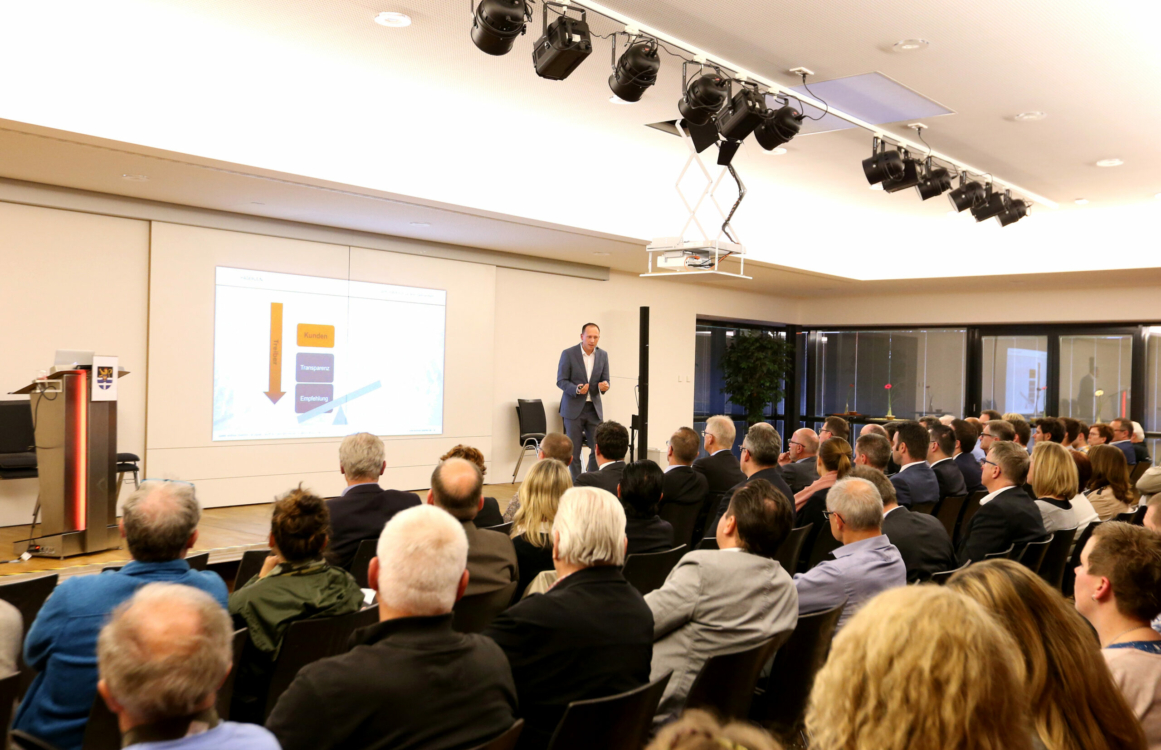 Referent bei einem Vortrag vor mehreren Zuschauerinnen und Zuschauern